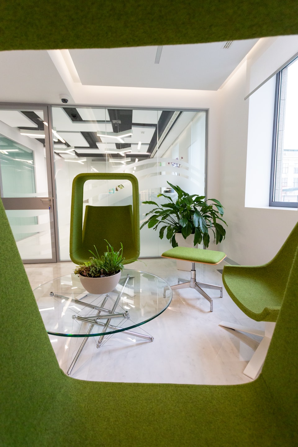 Lounge moderna con sedie verdi e piante.